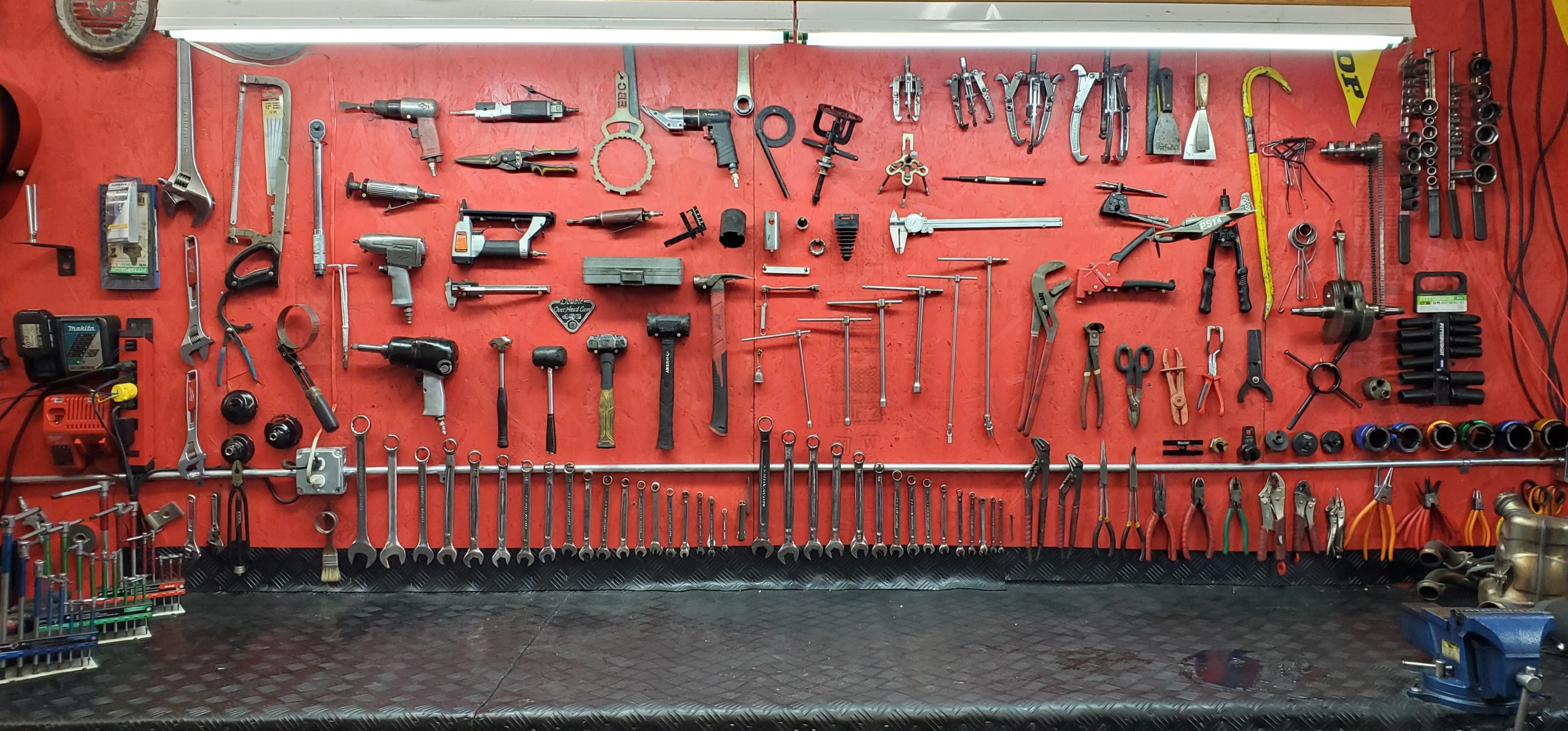 Workshop wall with various tools on a red background